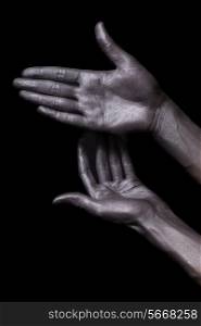 beautiful men hands with long fingers in silver paint on black background