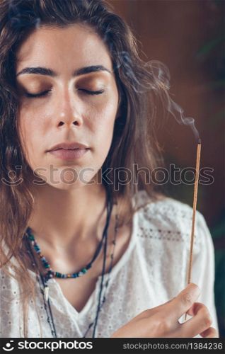 Beautiful mindfulness young girl relaxing and enjoying incense stick after yoga class.