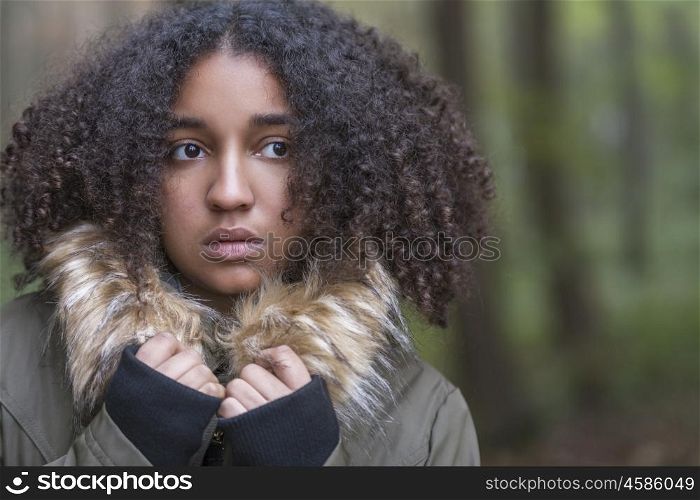 Beautiful mixed race African American girl teenager female young woman outside in a forest looking scared sad depressed or thoughtful