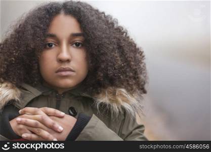 Beautiful mixed race African American girl teenager female young woman outside in autumn or fall mist or fog looking sad depressed or thoughtful
