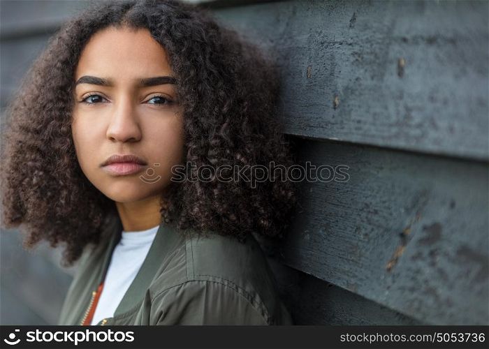 Beautiful mixed race African American girl teenager female young woman outside looking sad depressed or thoughtful