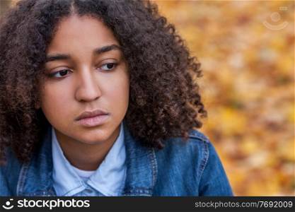 Beautiful mixed race African American girl teenager female young woman outside looking sad depressed or thoughtful, mental health concept