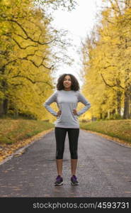 Beautiful mixed race African American young woman girl teenager fitness running jogging in Autumn Fall trees