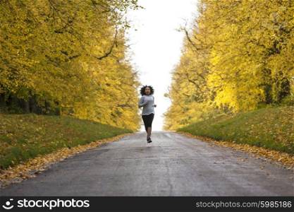 Beautiful mixed race African American young woman girl teenager fitness running jogging in Autumn Fall trees