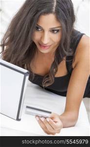 Beautiful mixed race Hispanic Latina woman using a credit card to shop on line using the internet and a tablet computer