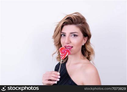 Beautiful model Girl holds lollipop in heart shaped red candy.Holiday concept with isolated background.