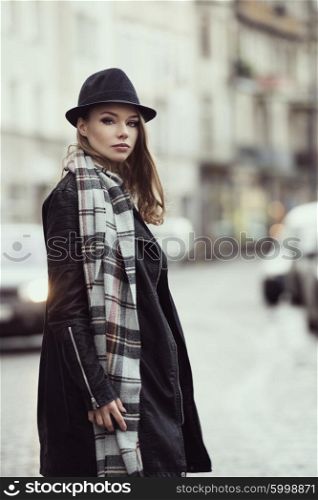 beautiful model , in winter dress with hat and scarf , walking in the middle of the road , looking in camera , she has freckles on face