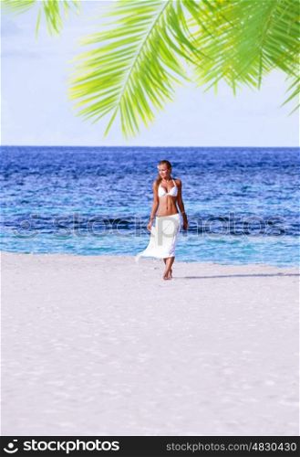 Beautiful model walking on the beach, wearing sexy white swimsuit and skirt, luxury photo shoot on Maldives, summer holidays concept