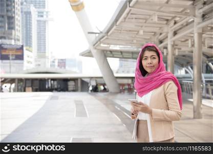 Beautiful Modern Arab Businesswoman wear hijab Using Mobile Phone in the big city.