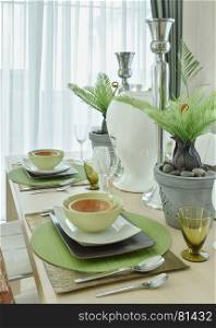 Beautiful modern ceramic tableware in green color scheme setting on dining table