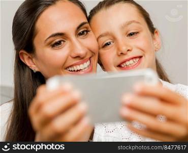 Beautiful Mom and Daughter at home, showing something on the phone