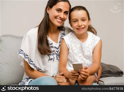 Beautiful Mom and Daughter at home, showing something on the phone
