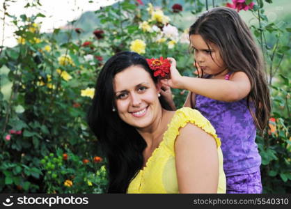 beautiful mom and daughter outdoor in garden together with flower have fun and hug