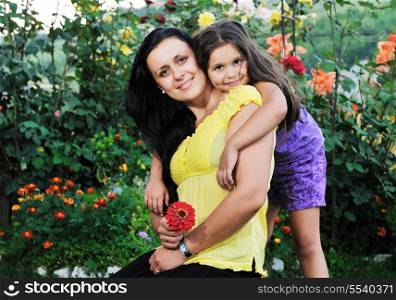 beautiful mom and daughter outdoor in garden together with flower have fun and hug
