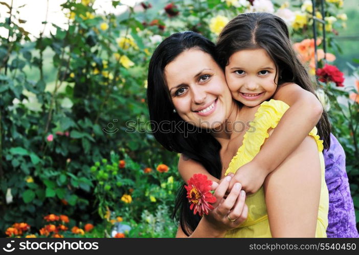 beautiful mom and daughter outdoor in garden together with flower have fun and hug