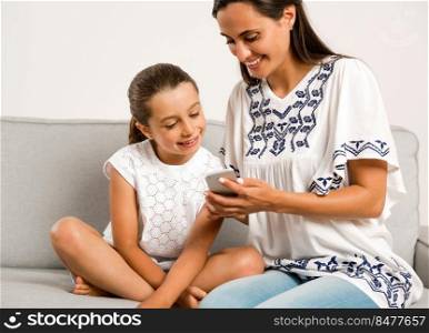 Beautiful Mom showing to her daughter something on her phone
