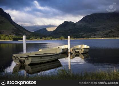 Beautiful moody stormy sky formations over stunning mountains lake landscape with rowing boats in foreground