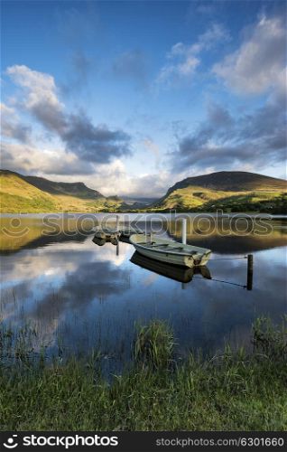 Beautiful moody stormy sky formations over stunning mountains lake landscape with rowing boats in foreground