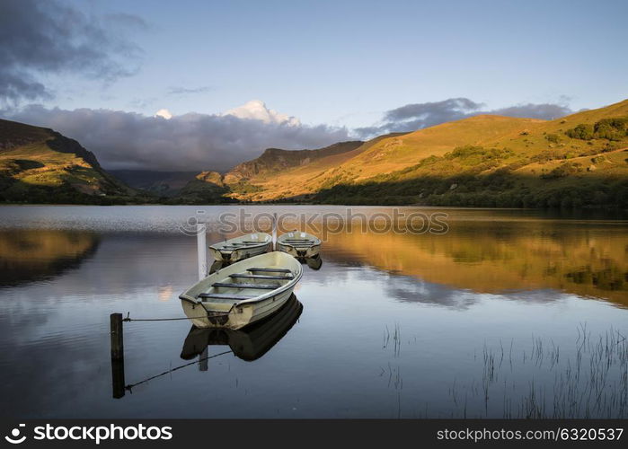 Beautiful moody stormy sky formations over stunning mountains lake landscape with rowing boats in foreground