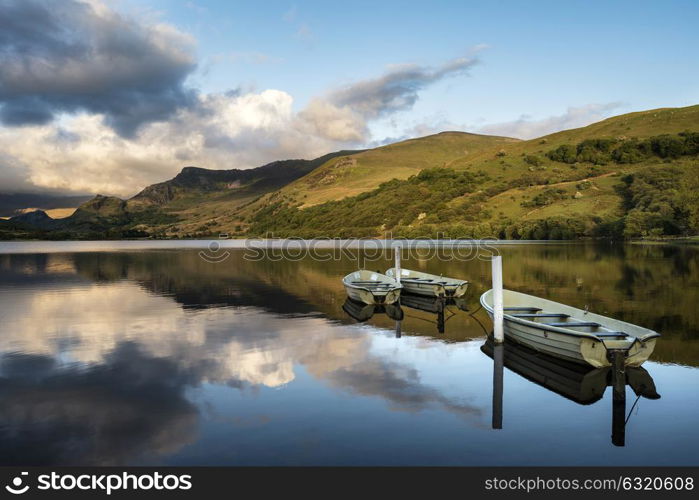 Beautiful moody stormy sky formations over stunning mountains lake landscape with rowing boats in foreground