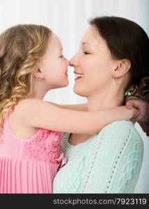 Beautiful mother and daughter touching each other with their noses. Lovely family portrait . Mother and daughter touching with noses