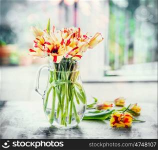 Beautiful mottled tulips bunch in glass vase at window with spring nature. Parrot tulips bouquet