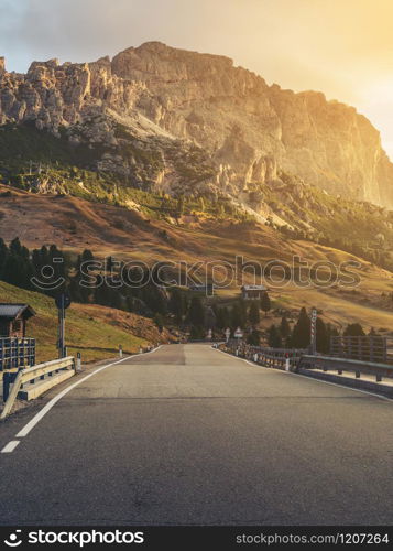 Beautiful mountain road with trees, forest and mountains in the backgrounds. Taken at state highway road of Passo Gardena in Dolomites mountain in Italy.