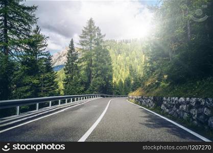 Beautiful mountain road with trees, forest and mountains in the backgrounds. Taken at state highway road of Dolomites mountain in Italy.