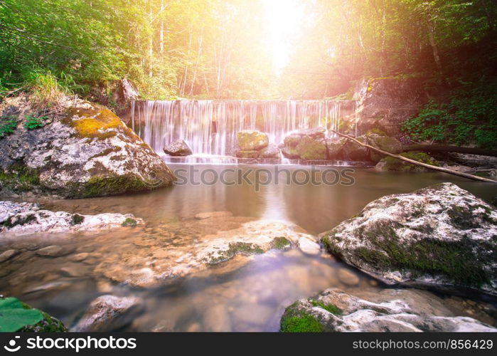 Beautiful mountain waterfall and sunlight in the forest, long time exposure. Austria.