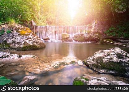 Beautiful mountain waterfall and sunlight in the forest, long time exposure. Austria.