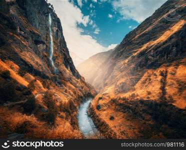 Beautiful mountains covered orange grass in autumn. Colorful landscape with mountain valley, river, waterfall, meadows and forest, sky with clouds in fall at sunset. Travel in Himalayas. Nature. Beautiful mountains covered orange grass in autumn