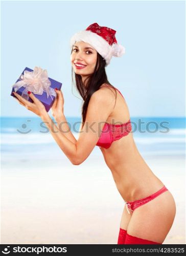 Beautiful mrs claus with gift wearing in bikini costume on beach