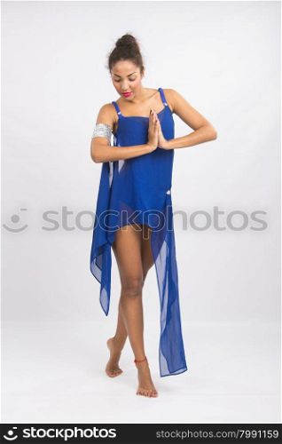Beautiful mulatto dancer performs a dance elements, isolated on a light background