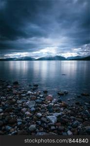 Beautiful mystic landscape lake scenery in Scotland with cloudy sky and sunbeams
