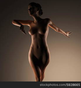 Beautiful naked young woman in the dark studio