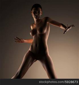 Beautiful naked young woman in the dark studio