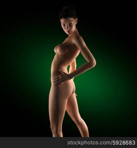 Beautiful naked young woman in the dark studio