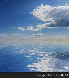 Beautiful natural background: blue sky with white clouds reflected in a water surface with small waves. Blue sky with white clouds and sea
