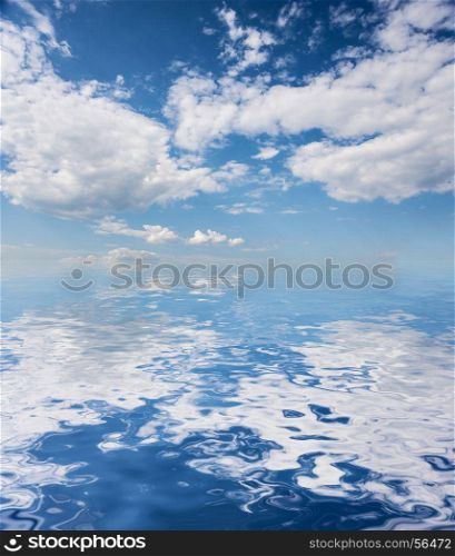 Beautiful natural background: blue sky with white clouds reflected in a water surface with small waves