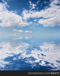 Beautiful natural background: blue sky with white clouds reflected in a water surface with small waves