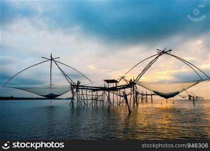Beautiful nature landscape golden light of the morning sky at sunrise and native fishing tool rural lifestyle at Pakpra canal, Songkhla Lake, Baan Pak Pra is a famous landmark of Phatthalung, Thailand. Rural lifestyle at Pakpra canal during sunrise in Thailand