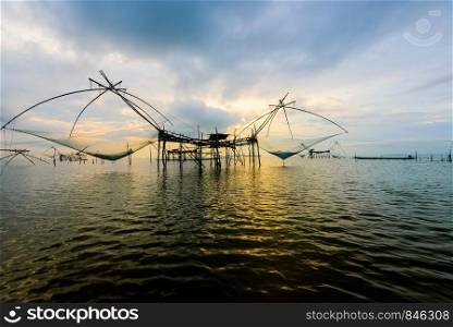 Beautiful nature landscape golden light of the morning sky at sunrise and native fishing tool rural lifestyle at Pakpra canal, Songkhla Lake, Baan Pak Pra is a famous landmark of Phatthalung, Thailand. Rural lifestyle at Pakpra canal during sunrise in Thailand