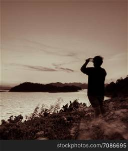 Beautiful nature landscape of mountain with lake, silhouette man take photo with smart phone. Vintage color style