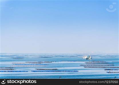 Beautiful nature landscape of the blue sea under the blue sky and floating buoys for mussel or Perna Viridis farming, boats and coastal fishing at Ko Loi or Koh Loy island in Chon Buri, Thailand. Mussel or Perna Viridis farming in Thailand