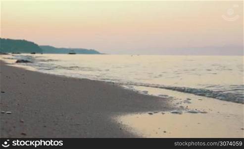 Beautiful nature scene. Quiet sea waves washing the shore at sunset. Clear sky in warm evening colors