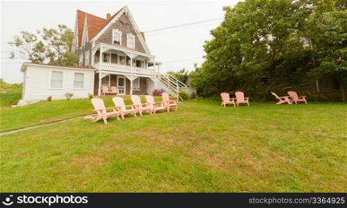 Beautiful New England vacation summer home with a row of pink lawn chairs.