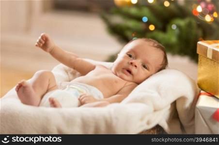 Beautiful newborn baby boy lying in basket at living room decorated for Christmas