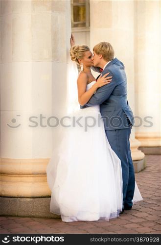 Beautiful newly married couple kissing against old column