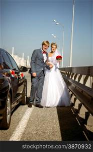 Beautiful newly married couple walking on highway at sunny day