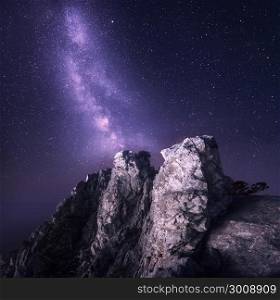 Beautiful night landscape with rocks and starry sky on the background of purple Milky Way, Magic Universe, mountains.
